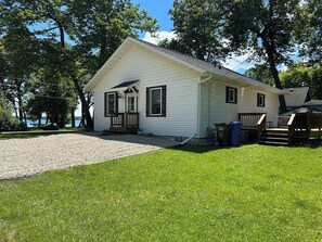A single-story white house with a porch, a deck, and a gravel driveway. - 2 Bedroom with 2 minute walk to the sandy beach of Lake Melissa (Detroit Lakes)