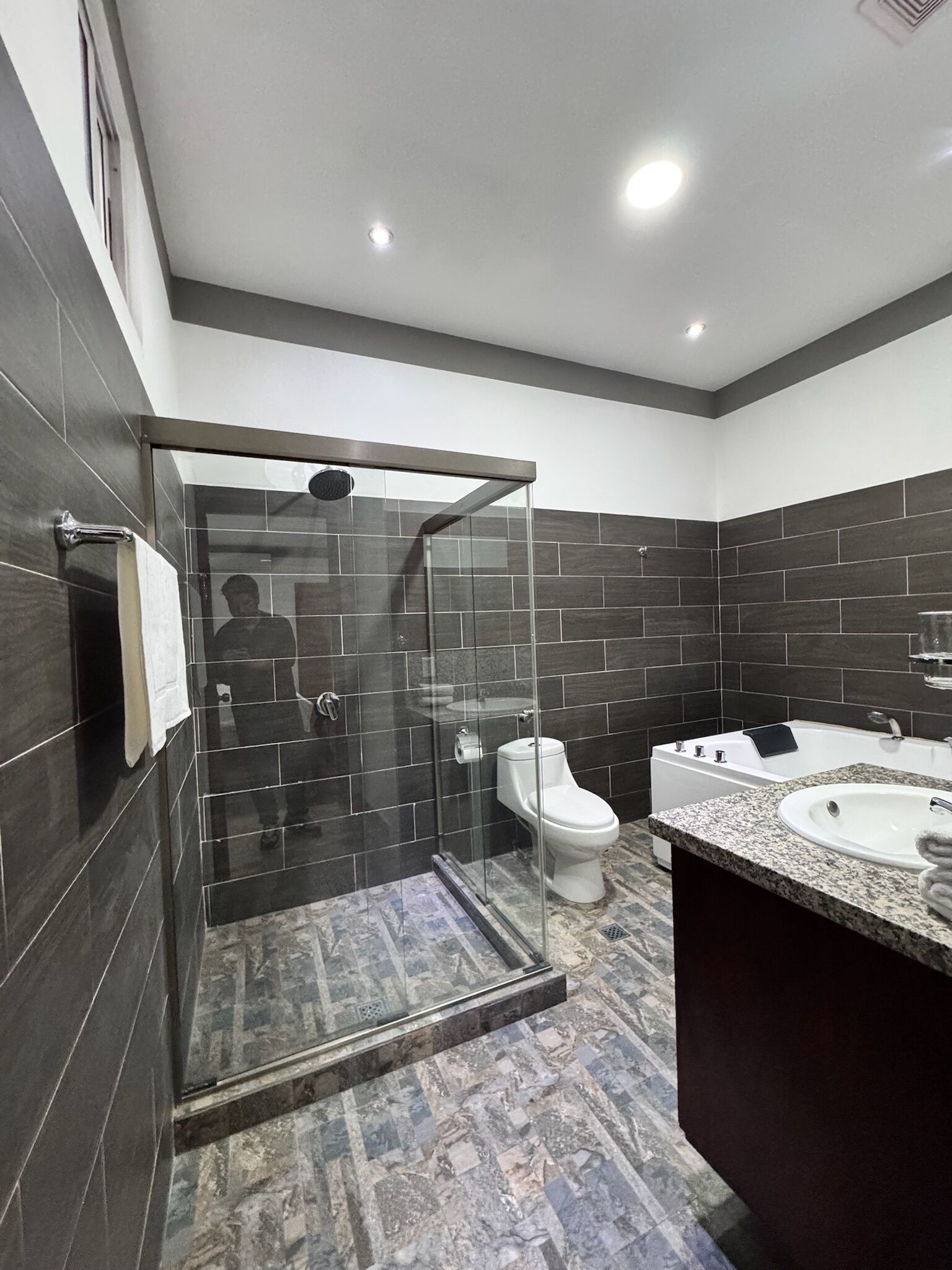 Un baño moderno con ducha envuelta en cristal, inodoro y tocador con lavabo.