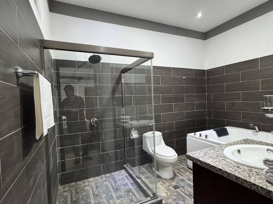 Un baño moderno con ducha envuelta en cristal, inodoro y tocador con lavabo.