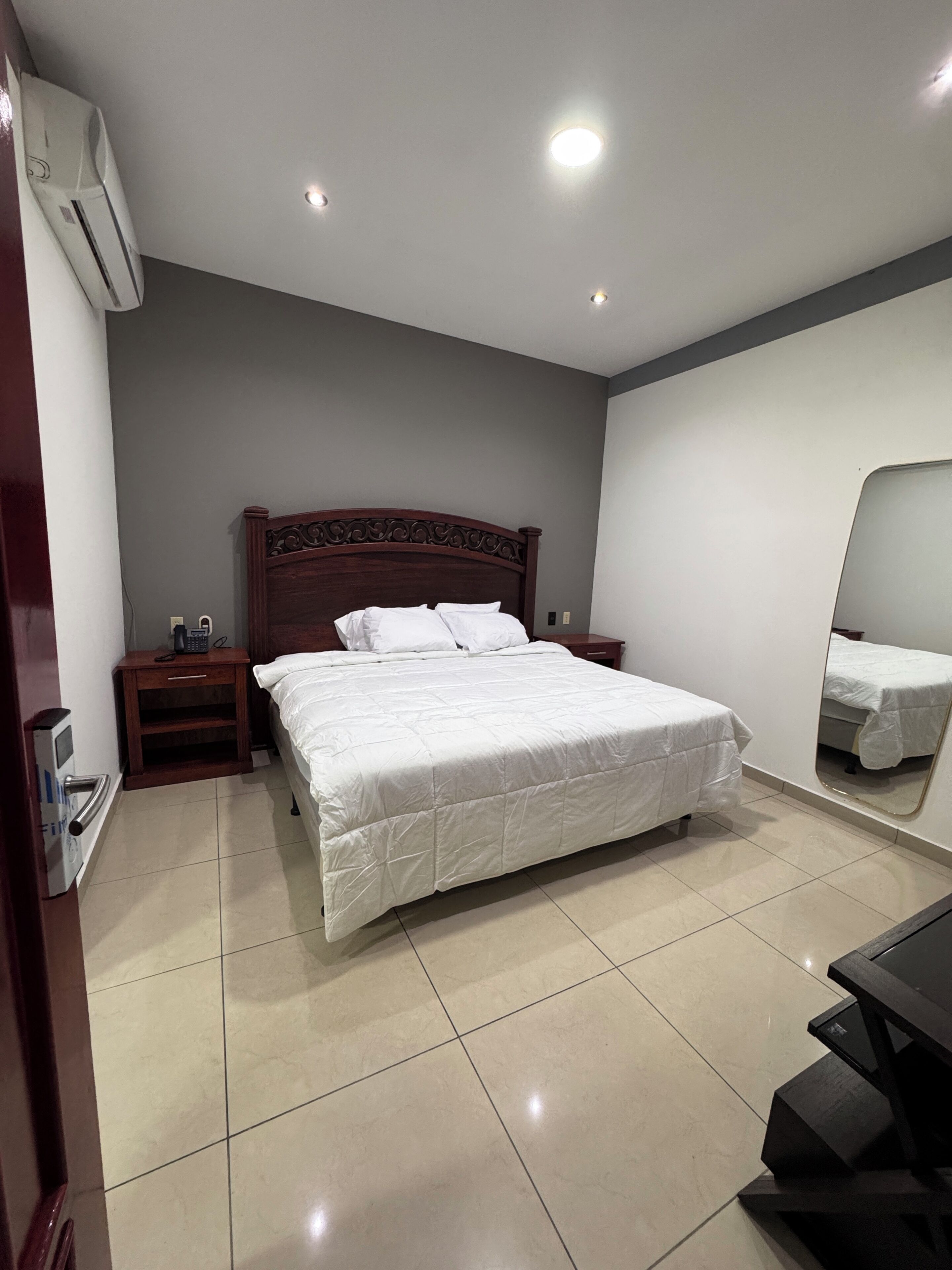 Une chambre à coucher avec un lit, une table de chevet, un miroir et un bureau.
