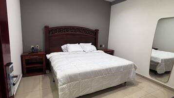 Un dormitorio con cama, mesita de noche, espejo y escritorio.