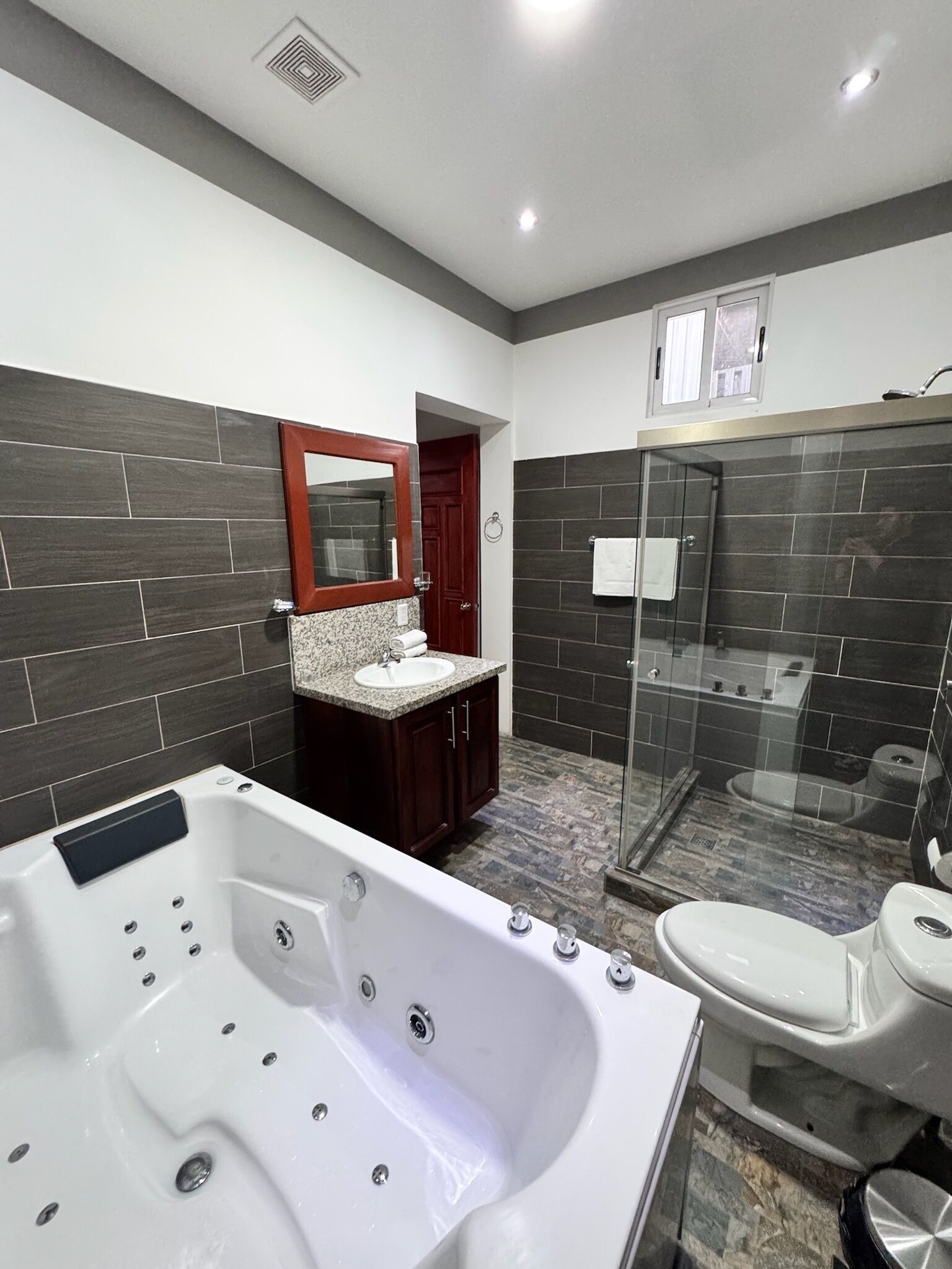 Une salle de bain moderne avec une grande baignoire, une douche à l’italienne et des toilettes.