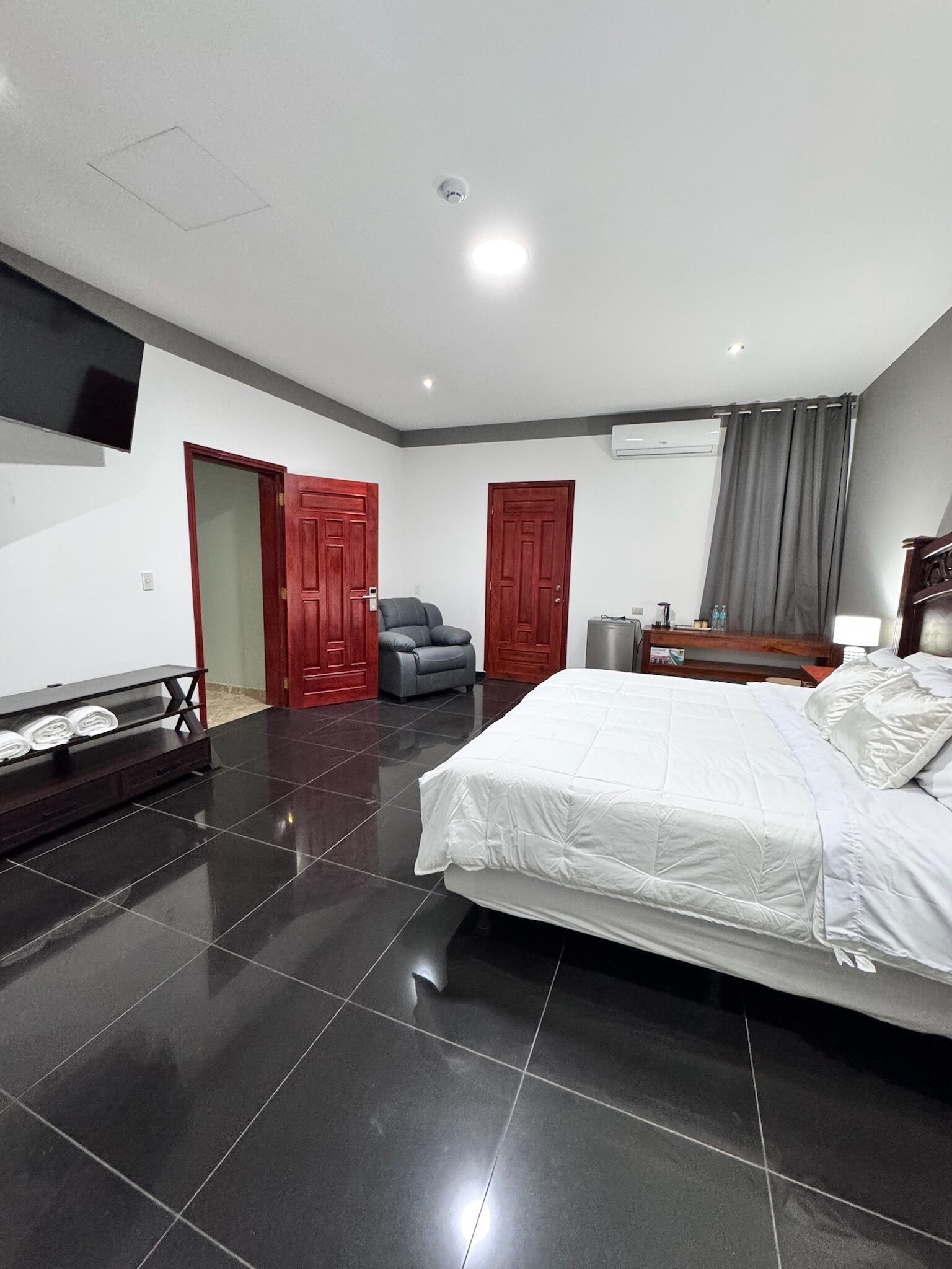 A bedroom with a bed, a TV, a chair, and a wardrobe.