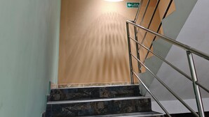 Un escalier avec des marches en marbre, des rampes en métal et un luminaire suspendu.