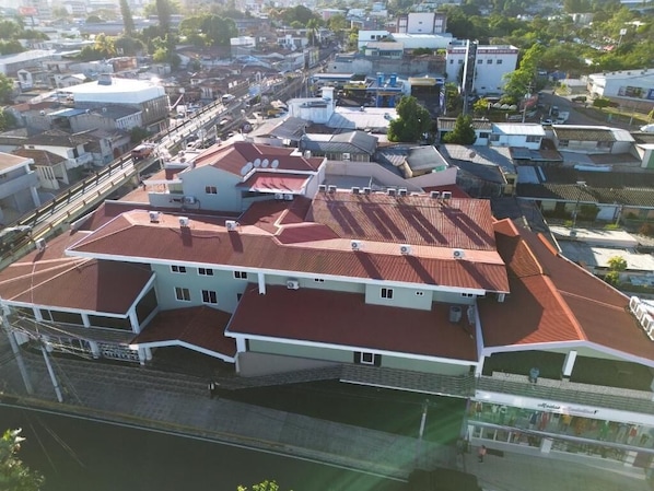 A multi-story building with a red-tiled roof, white walls, and a flat facade.