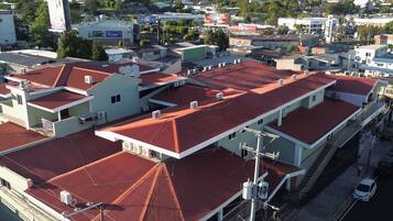 A multi-story building with red-tiled roofs, a central staircase, and a street view with cars and pedestrians.