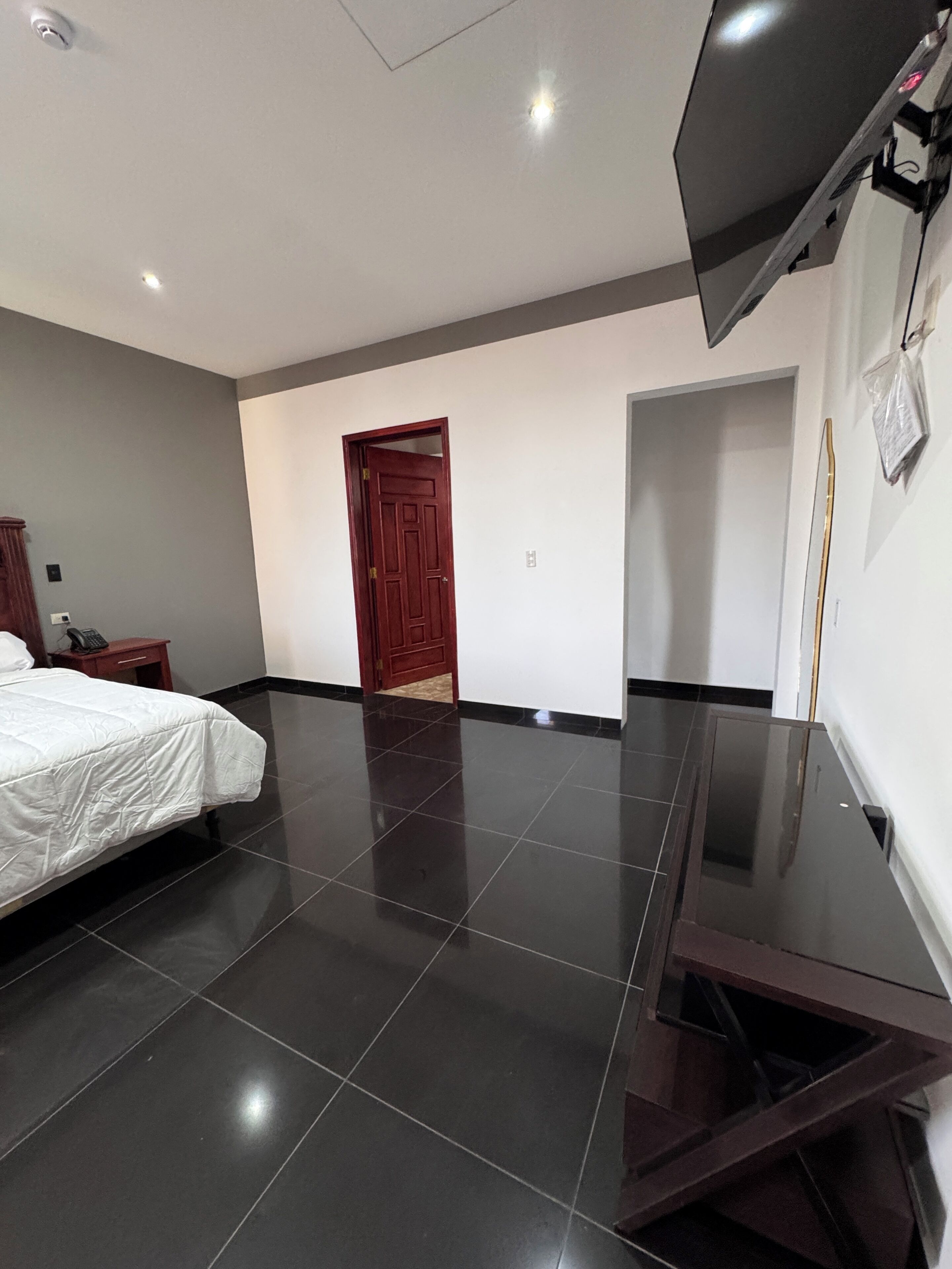 Une chambre d’hôtel avec un lit, un bureau, une télévision et une porte.