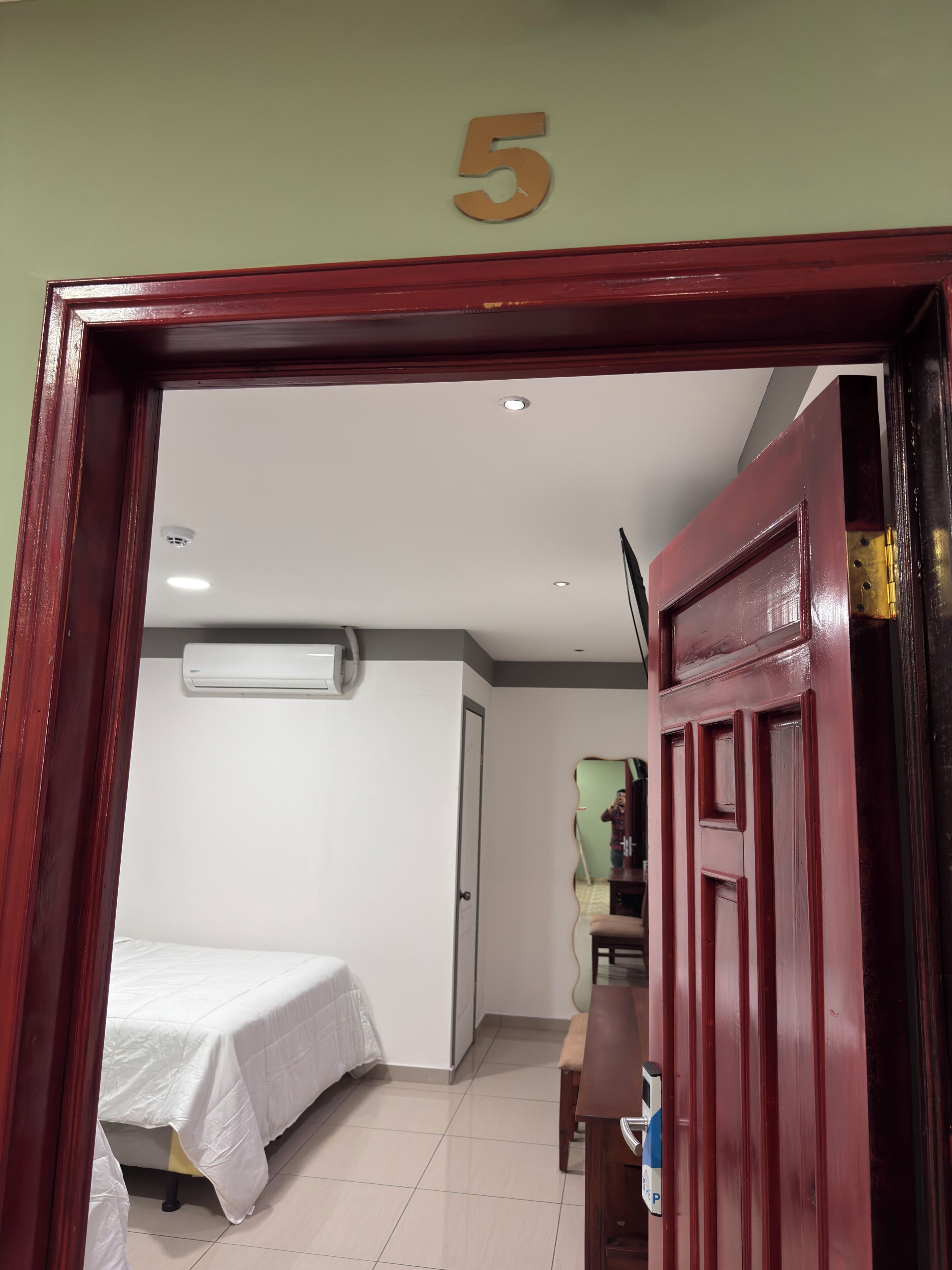 A room with a bed, a desk, a chair, and a door with the number 5.