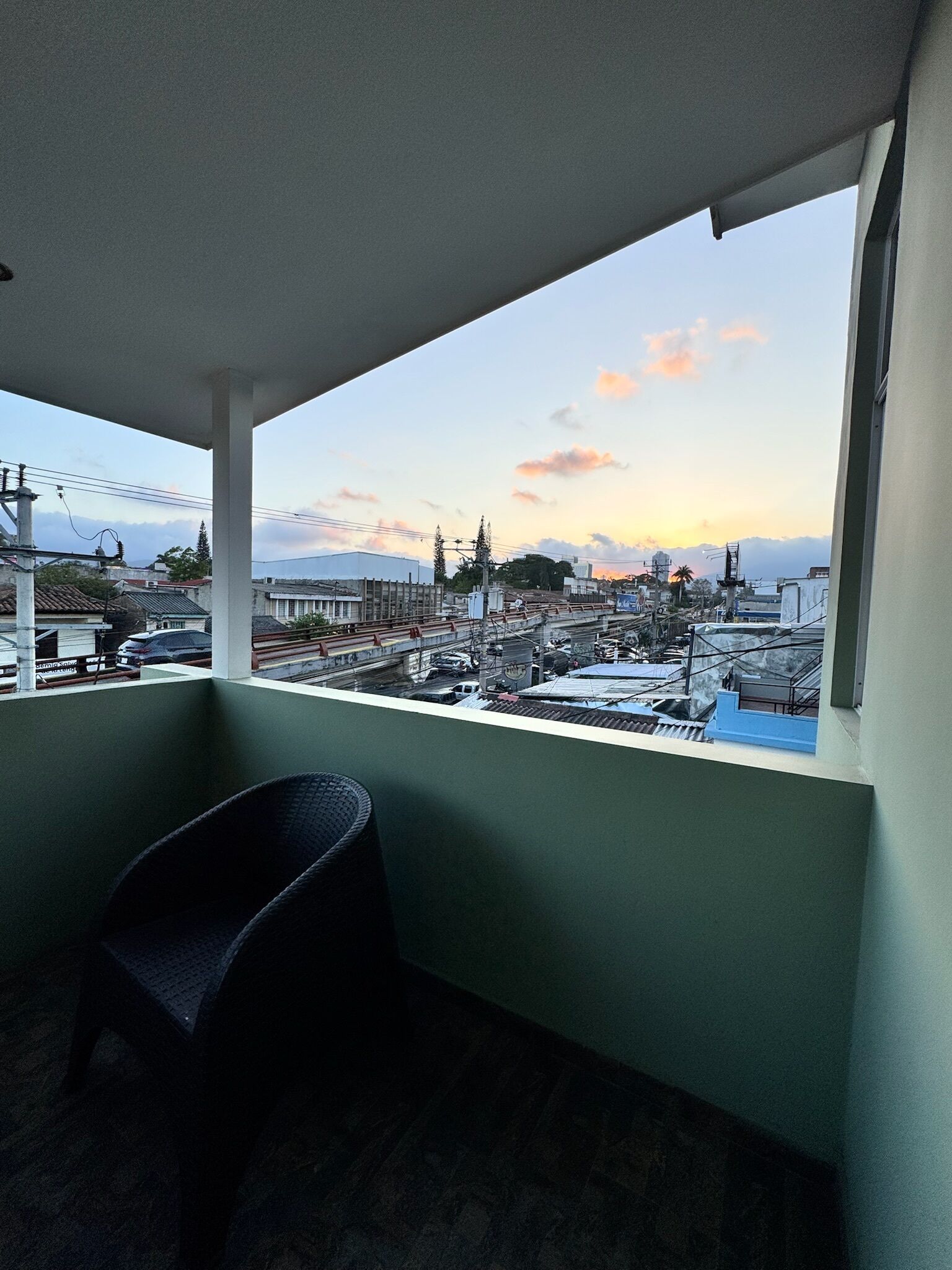 A balcony with a view of a cityscape during sunset.