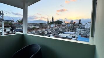 A balcony with a view of a cityscape during sunset.