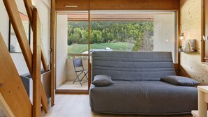 A room with a large bed, a chair, and a view of a forest through a sliding door. - Elegant 'Havre de Paix' Apartment with Mountain View, Private Terrace & Wi-Fi (Villard-de-Lans)