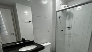 A modern bathroom with a white sink, toilet, and glass shower enclosure. - Apartment in the Green Tower Building (Maceió)