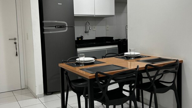 A compact kitchen with a refrigerator, cabinets, and a dining table with chairs. - Apartment in the Green Tower Building (Maceió)