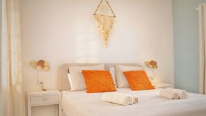 Una camera d'albergo ordinata con un letto, cuscini, un comodino e una lampada fissata al muro.