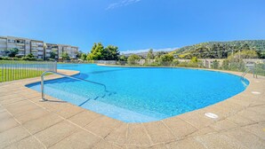 A swimming pool with a clear blue water, surrounded by a paved deck and a metal fence. - Terraluz Apartment 2D, Wifi & Parking (Papudo)