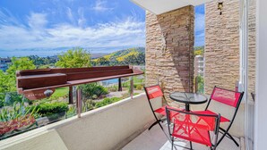 A balcony with a stone wall, a glass railing, and a view of greenery and hills. - Terraluz Apartment 2D, Wifi & Parking (Papudo)