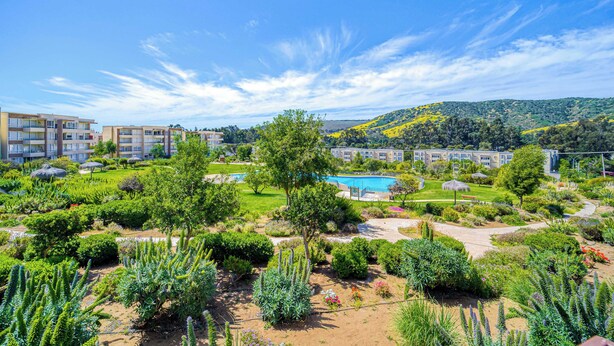A hotel with a pool, garden, and multiple buildings in the background. - Terraluz Apartment 2D, Wifi & Parking (Papudo)