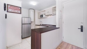 A compact kitchen with white cabinets, a built-in microwave, and a refrigerator. - Terraluz Apartment 2D, Wifi & Parking (Papudo)