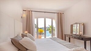 A bedroom with a bed, a nightstand, a mirror, and a view of the outdoors. - Holiday Home 'Ses Gavines en Cala Moragues' with Sea View, Wi-Fi and Air Conditioning (Andratx)