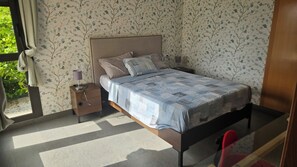 A bedroom with a bed, nightstand, and a window with curtains. - Luxury apartment with a view of the sea (VC)