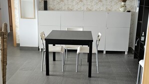 A modern kitchen with a dining table, chairs, a cabinet, and a decorative vase. - Luxury apartment with sea view (VC)