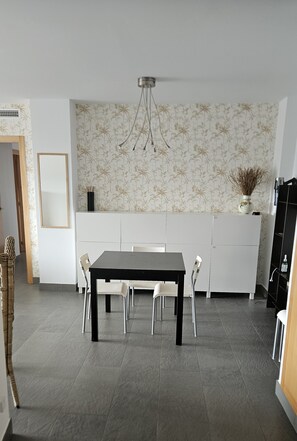 A modern kitchen with a dining table, chairs, a cabinet, and a decorative vase. - Luxury apartment with sea view (VC)