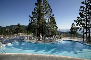 Una piscina con sillas de descanso y vistas a las montañas.