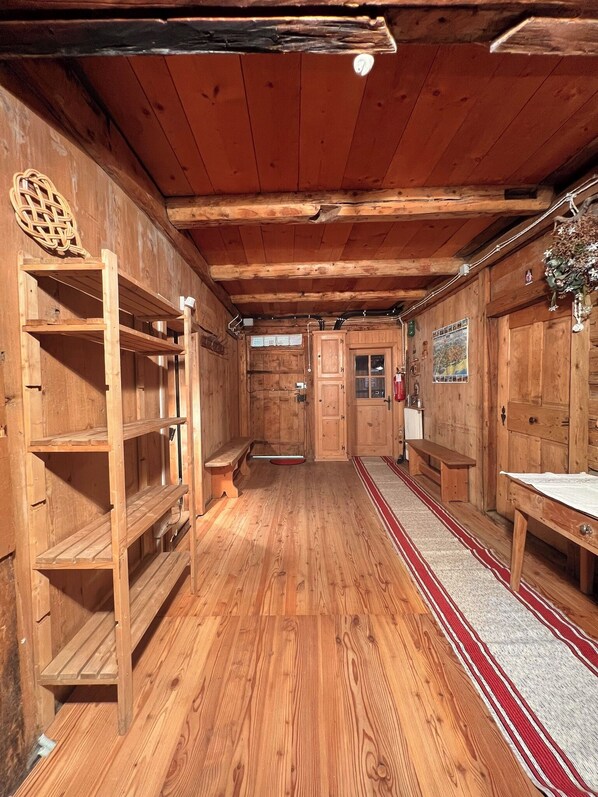 A wooden interior with shelves, benches, and a patterned rug.