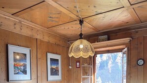 A wooden interior with a table, chairs, a hanging lamp, framed pictures, and a window with a view. - Chalet from 1792, authentic alpine soul full of tradition and history without filters (Andraz)