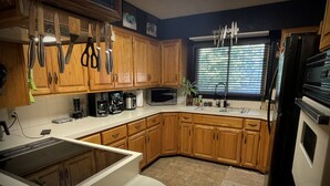 A kitchen with wooden cabinets, a microwave, a coffee maker, and a sink.