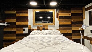 A bed with a white duvet, a wooden headboard, and a mirror above it.