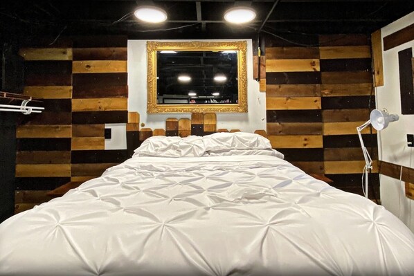 Un lit avec une couette blanche, une tête de lit en bois et un miroir au-dessus.