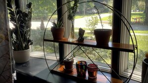 A window with a metal shelf holding potted plants and decorative items.