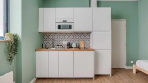 Cocina compacta con armarios blancos, microondas y salpicadero decorado.
