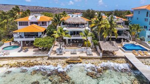 Un resort frente a la playa con varias edificaciones, una piscina y un litoral rocoso.