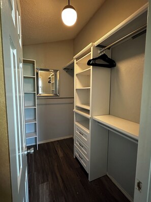 Un dressing avec des étagères ouvertes, une tringle et un miroir.
