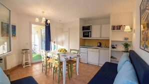 A compact living space with a dining area, kitchenette, and a sofa. - Apartment with pools and garden near the beach (La Baule-Escoublac)