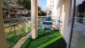 A balcony with artificial grass, a railing, and a table with chairs. - Apartment with pools and garden near the beach (La Baule-Escoublac)