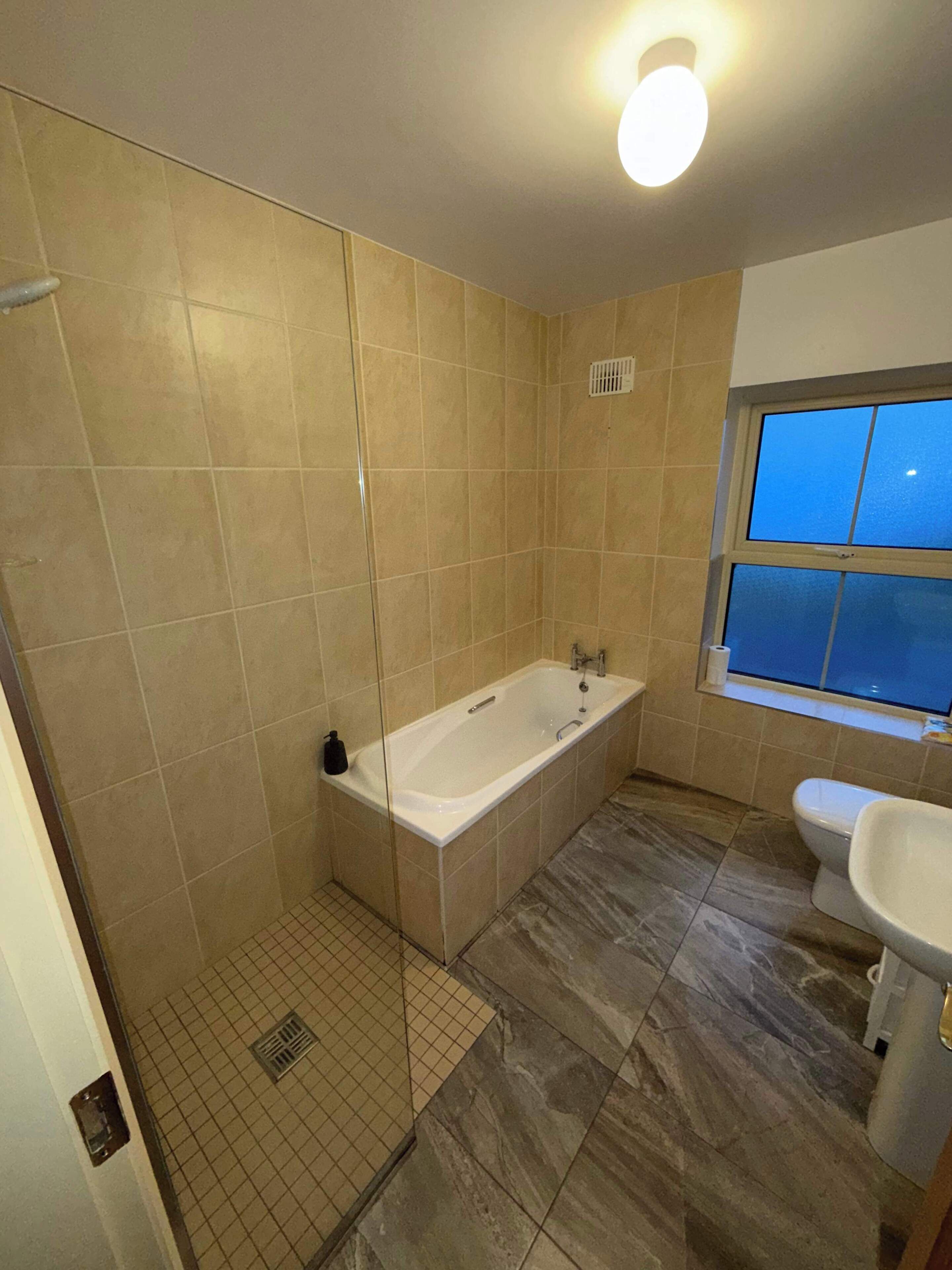 A bathroom with a bathtub, a sink, and a window.