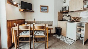 Et kompakt køkken med spiseplads, træskabe, en mikrobølgeovn og et lille køleskab.