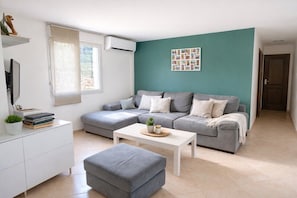 Ein modernes Wohnzimmer mit einem grauen Ecksofa, einem weißen Couchtisch und einer weißen Kommode.
