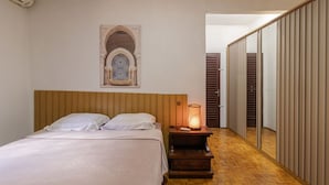Ein Schlafzimmer mit einem Bett, einem Nachttisch mit Lampe, einer dekorativen Wandnische und einem Schiebetürenschrank.