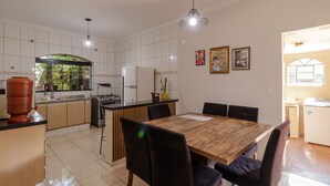 Eine moderne Küche mit Essbereich, ausgestattet mit einem Holztisch, Stühlen und einer hängenden Leuchte.
