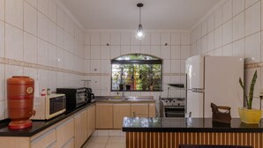 Eine moderne Küche mit weißen Fliesen, einer Kochinsel, einer Mikrowelle, einem Herd und einem Kühlschrank.