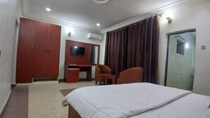 Ett hotellrum med en säng, ett skrivbord, två stolar, en TV och en garderob.