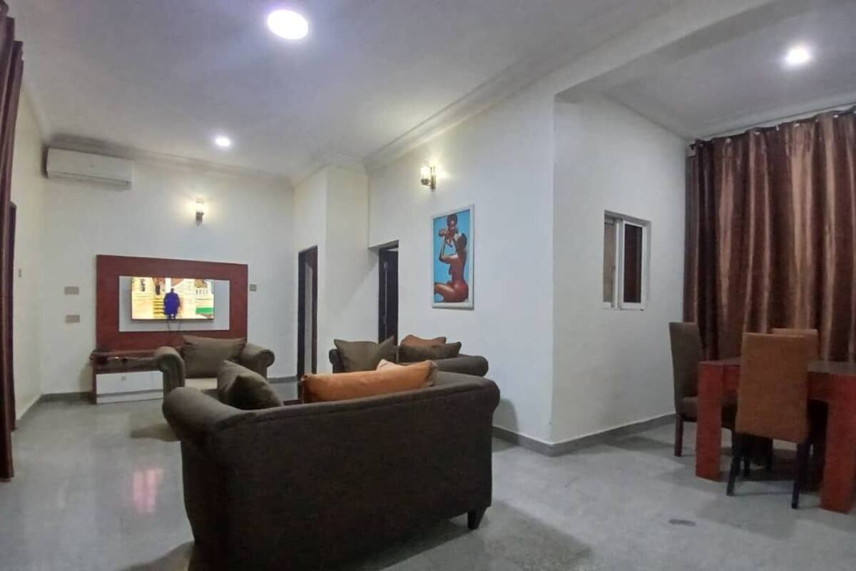 A living room with a sofa, a TV, and a dining area with chairs and a table.