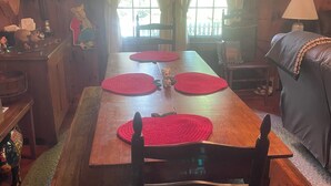 A wooden dining table with red placemats, a chair, a sofa, and a lamp. - Superb 5-bedroom house walking distance to charming downtown Saluda (Saluda)