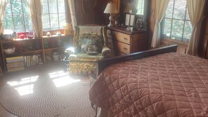 A cozy room with a large bed, wooden floors, a dresser, a chair, and a window with curtains. - Superb 5-bedroom house walking distance to charming downtown Saluda (Saluda)