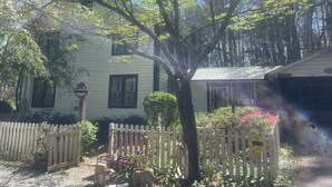 A white house with a fenced yard, a tree, and a pig sign. - Superb 5-bedroom house walking distance to charming downtown Saluda (Saluda)