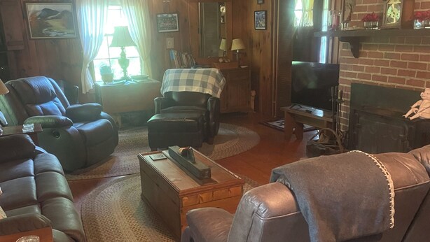 A cozy living room with a fireplace, leather sofas, a television, and a wooden ceiling. - Superb 5-bedroom house walking distance to charming downtown Saluda (Saluda)